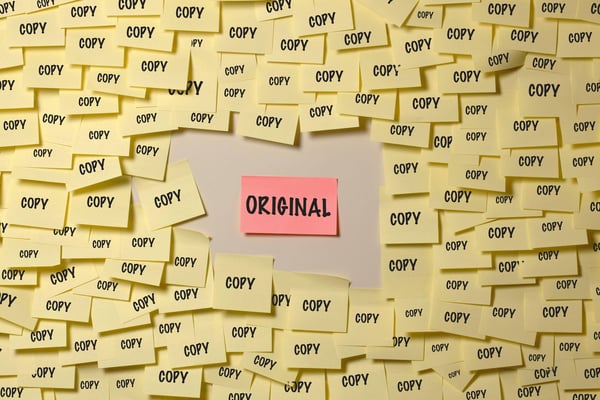 Yellow post-its with the word copy surround a larger orange post-it with the word original represents the chaos caused when there are uncontrolled copies of a document