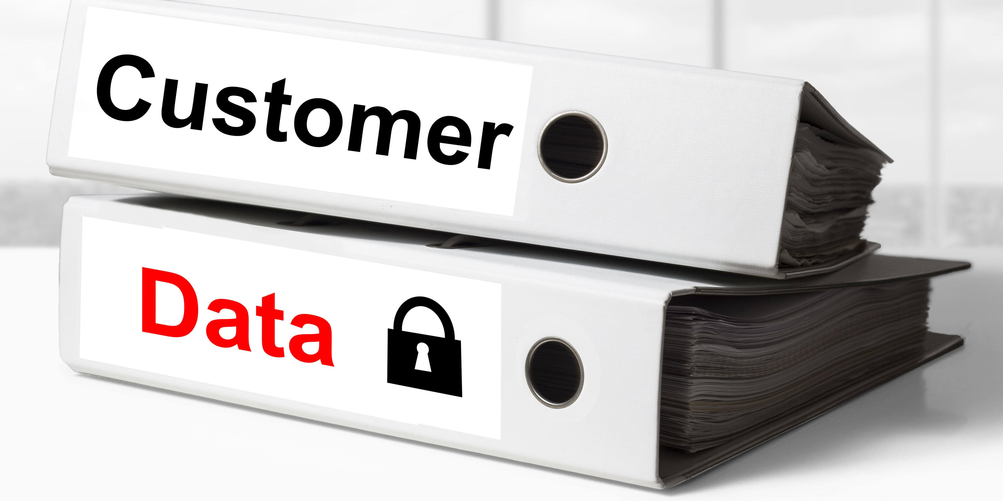 stack of two white office binders with the words customer data on the spines represent the difficulty of ensuring data privacy using paper documents
