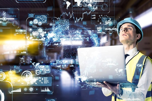 Employee in hard hat holding a laptop with background that represents new technology