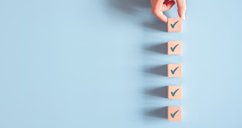 Eine Hand platziert Holzklötze mit Häkchen