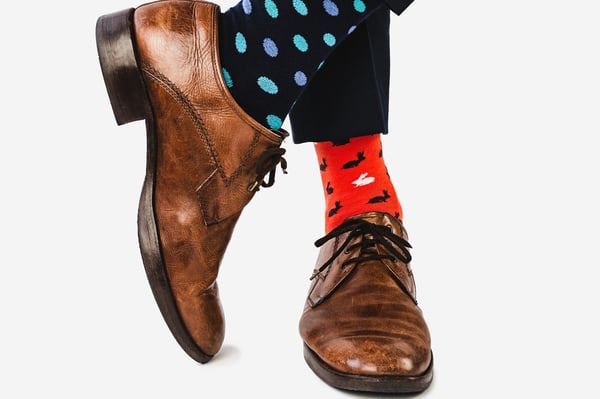 Close up photo of stylish shoes brown shoes and multicolored socks on a white background
