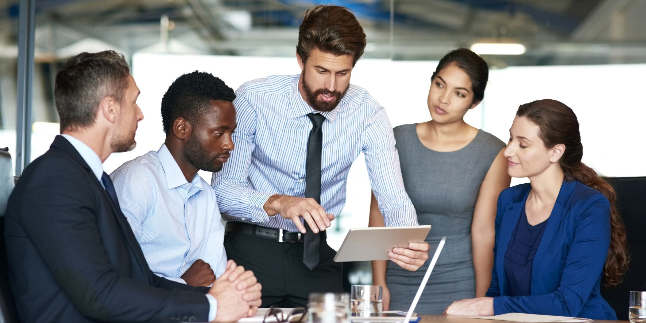 A group of businesspeople discussing artificial intelligence while looking at a digital tablet
