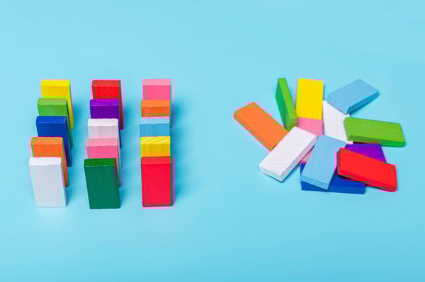 Chaotic unorganized colored dominoes contrast with carefully ordered rows representing how digitization turns chaos into order