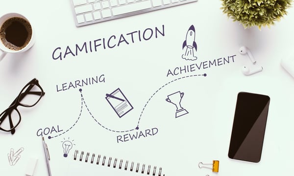 Gamification increase employee productivity with these steps:  Goal, Paper on a desk with the word gamification on it represents the potential for learning, rewards and achievement through gamification