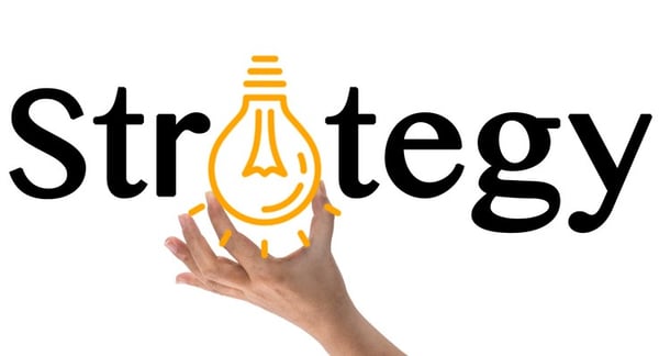 Hand holding a lightbulb which replaces the "a" in strategy