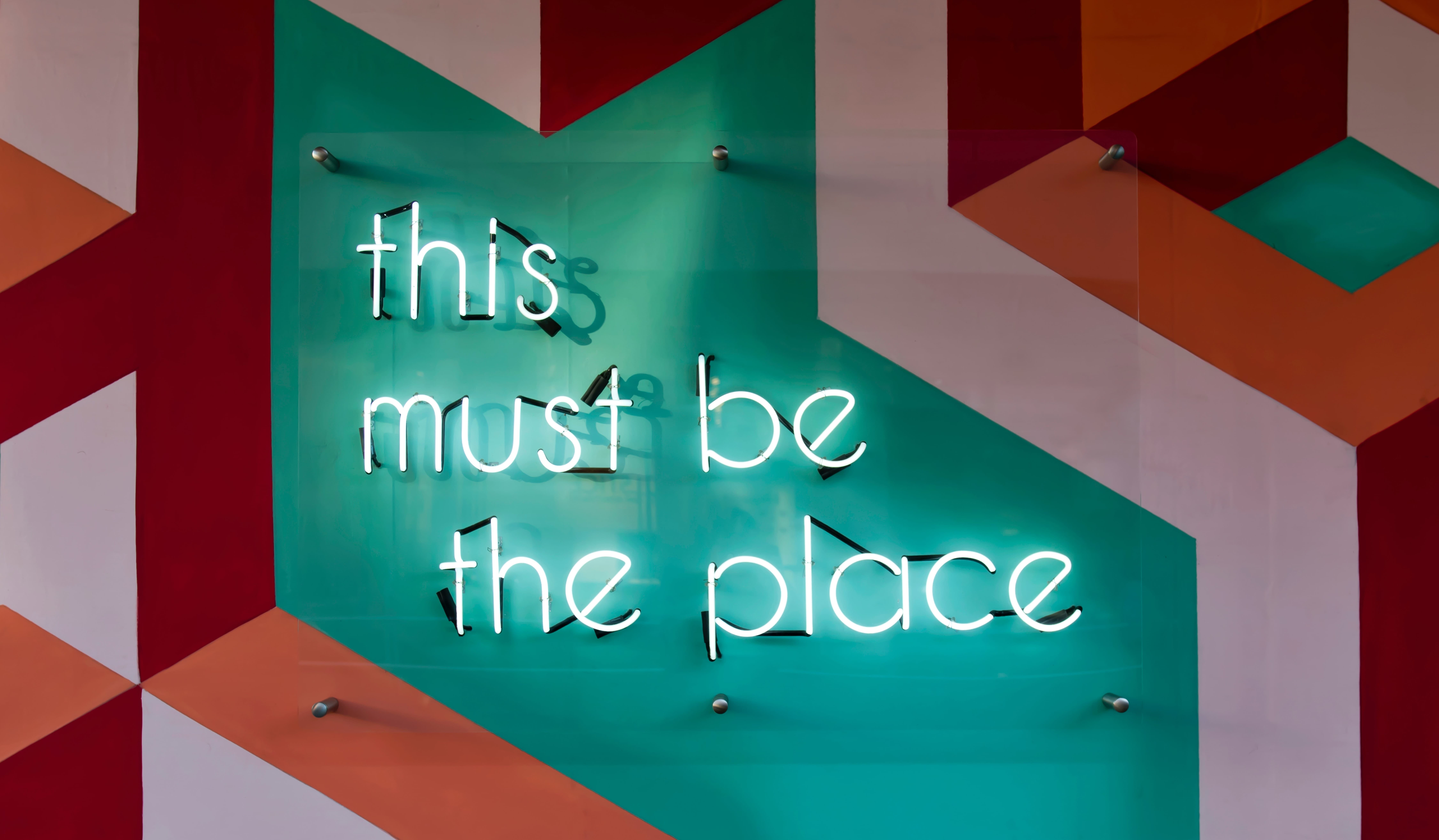 Sign lit up with neon lights that says this must be the place