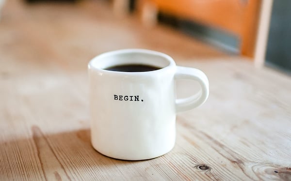 white coffee cup with begin written on it